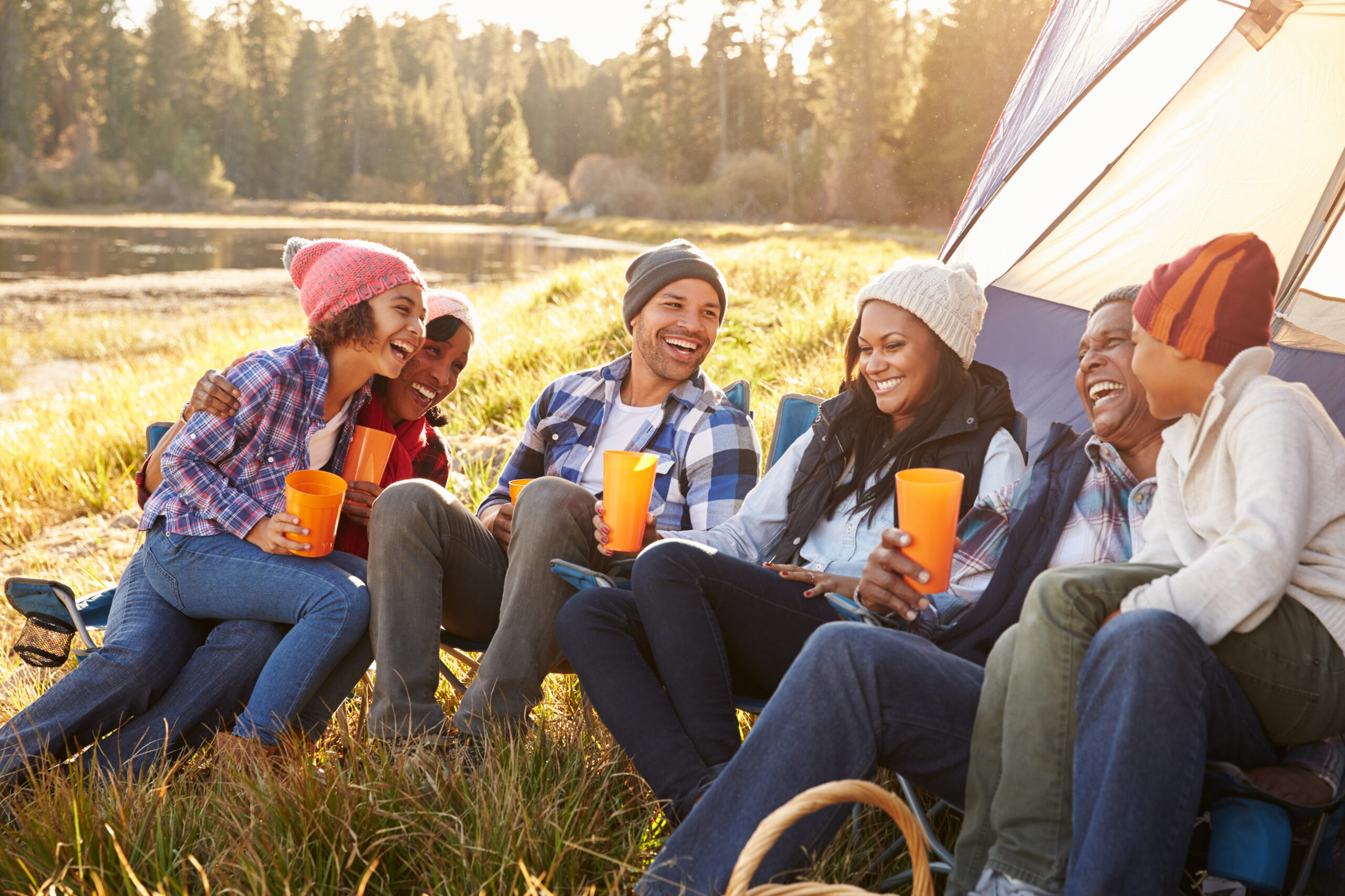A family of three generations laughing together outdoors in golden sunlight