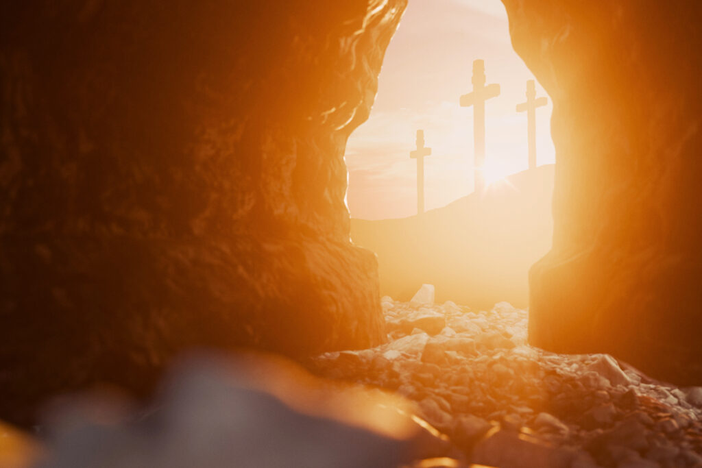 The view from an empty tomb toward three crosses at sunrise