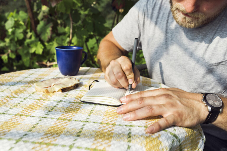 A man writing in a notebook outdoors